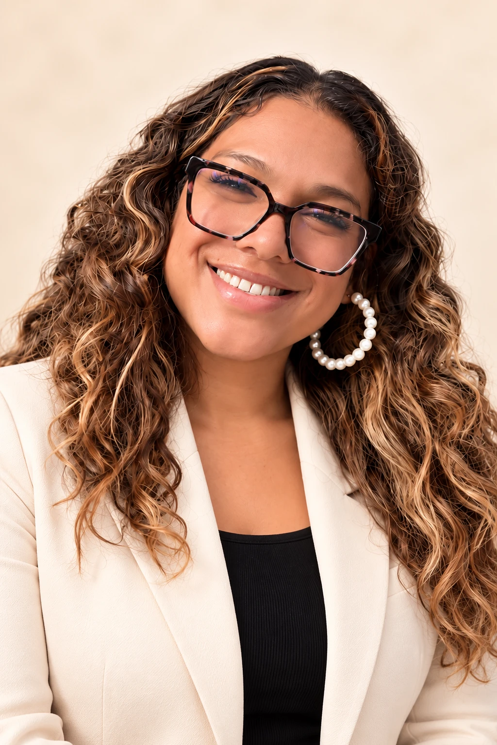 Carlita smiling in a warm cream blazer and glasses
